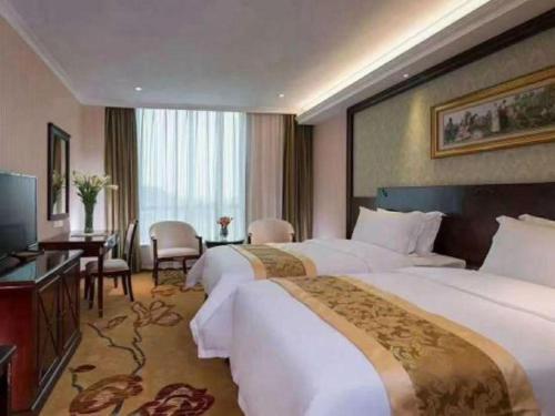 a hotel room with two beds and a desk at Vienna 3 Best Hotel Dongguan Fenggang Yongsheng Street in Tiantangwei