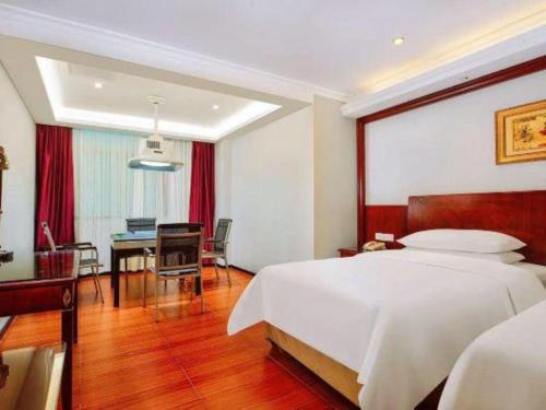 a bedroom with a large bed and a dining room at Vienna 3 Best Hotel Dongguan Fenggang Yongsheng Street in Tiantangwei