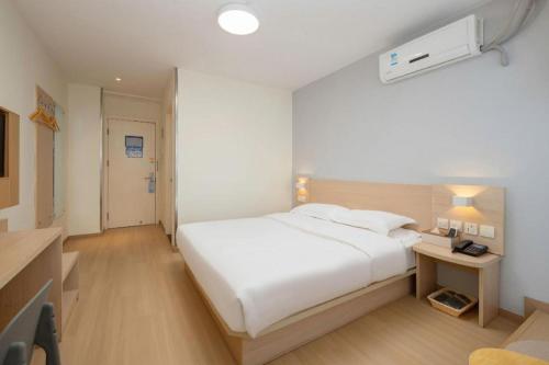 a bedroom with a large white bed and a desk at 7 Days Inn Suzhou Mudu Ancient Town Kaima Auto Market in Suzhou