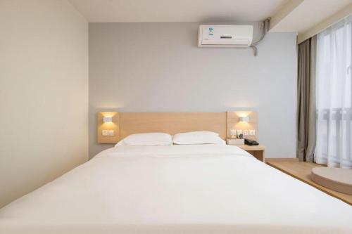 a bedroom with a large white bed with two pillows at 7 Days Inn Suzhou Mudu Ancient Town Kaima Auto Market in Suzhou