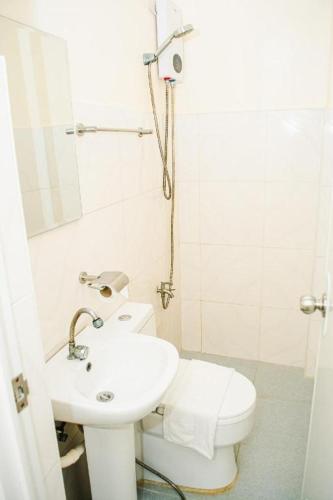 a white bathroom with a toilet and a sink at Sabine's Place in Masbate