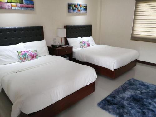 a bedroom with two beds with white sheets and a blue rug at Sabine's Place in Masbate