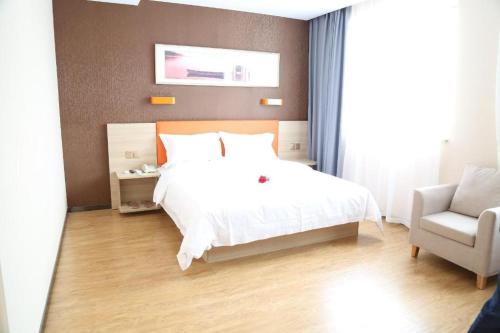 a bedroom with a white bed and a chair at 7 Days Premium Yancheng Dafeng Zhongjiao Meilu City in Yancheng