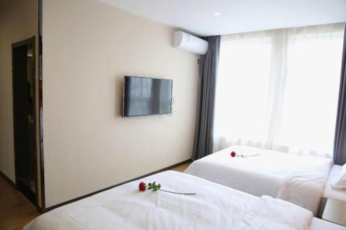a room with two beds and a tv on the wall at 7 Days Premium Yancheng Dafeng Zhongjiao Meilu City in Yancheng