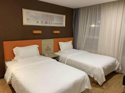 two beds in a hotel room with white sheets at 7 Days Premium Yancheng Dafeng Zhongjiao Meilu City in Yancheng