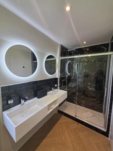 a bathroom with two sinks and a shower at Logis - Hostellerie Saint-Louis & Restaurant Pauze in Bollezeele