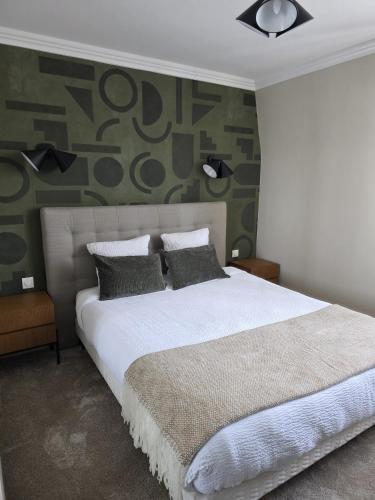 a bedroom with a large bed with a green wall at Logis - Hostellerie Saint-Louis & Restaurant Pauze in Bollezeele
