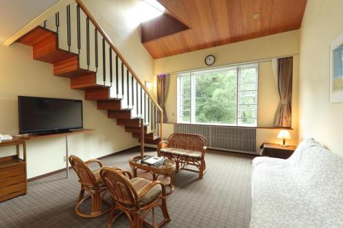 a living room with a staircase and a tv at Fuji Shoei kaikan in Fuji