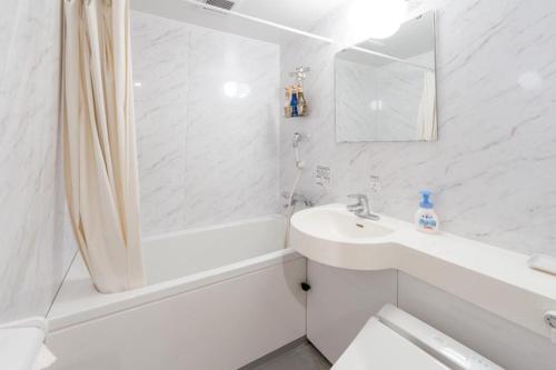a white bathroom with a sink and a shower at Fuji Shoei kaikan in Fuji