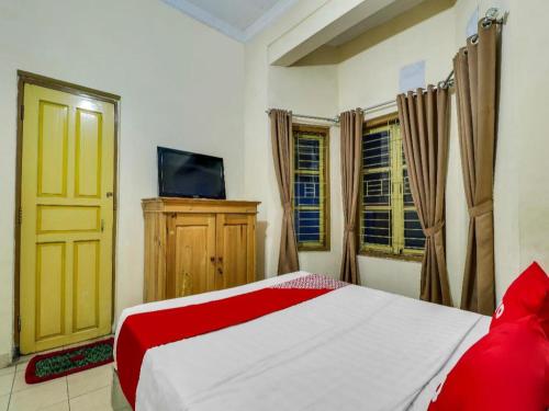 a bedroom with a bed and a tv and windows at Hotel O My Guest House Syariah in Bandung
