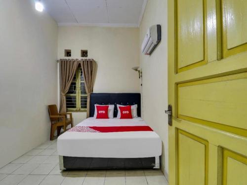 a bedroom with a bed with red pillows and a door at Hotel O My Guest House Syariah in Bandung