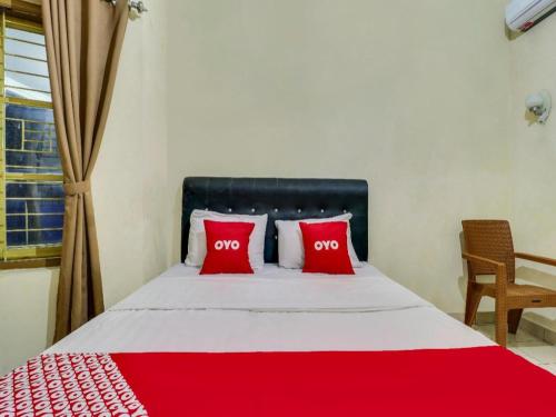 a bedroom with a red and white bed with red pillows at Hotel O My Guest House Syariah in Bandung