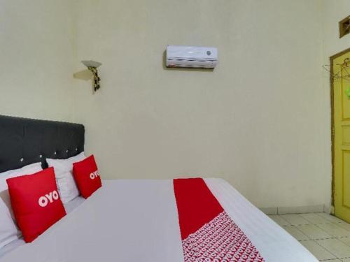 a bedroom with a bed with red pillows on it at Hotel O My Guest House Syariah in Bandung