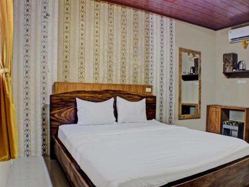 ein Schlafzimmer mit einem weißen Bett mit einem hölzernen Kopfteil in der Unterkunft Capital O 92681 Randu Mas Hotel & Resort Taman Purbakala in Gedung