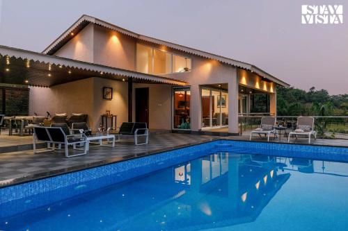 a house with a swimming pool in front of a house at StayVista's The Tavern At Canary Farms - Mountain-View Luxury Mansion with Infinity Pool & Games Zone in Lonavala