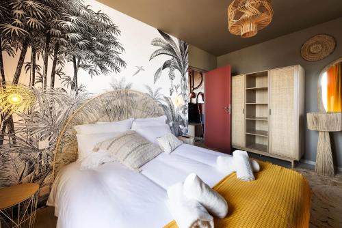 - une chambre avec un grand lit blanc et des palmiers sur le mur dans l'établissement Le terracotta T2 premium en centre bourg de Crozon, à Crozon