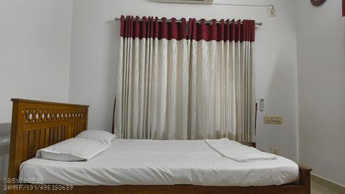 a bedroom with a bed and a window with curtains at The Mangosteen Homestay in Kodanad