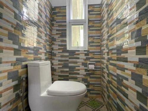a bathroom with a toilet and a mosaic wall at Pilot Hotel in Alaminos