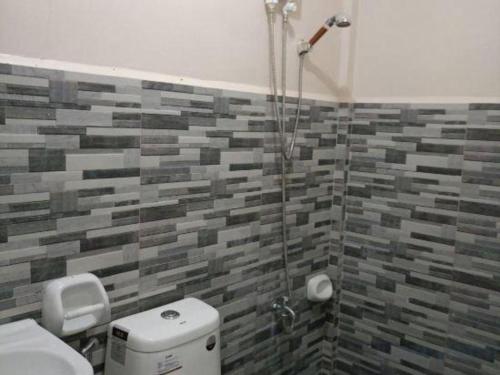 a bathroom with a shower with a toilet and a tile wall at Pilot Hotel in Alaminos