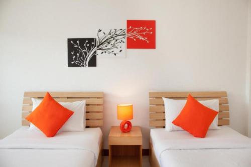 two beds with orange pillows in a room at Meesuk ChiangRai Hotel in Chiang Rai
