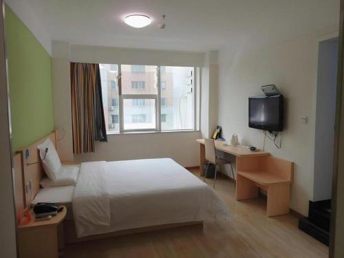 a hotel room with a bed and a desk and a television at 7Days Inn Xuzhou Normal University Yunlong Mountain in Xuzhou