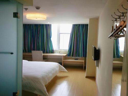 a bedroom with a bed and a desk and windows at 7Days Inn Xuzhou Normal University Yunlong Mountain in Xuzhou