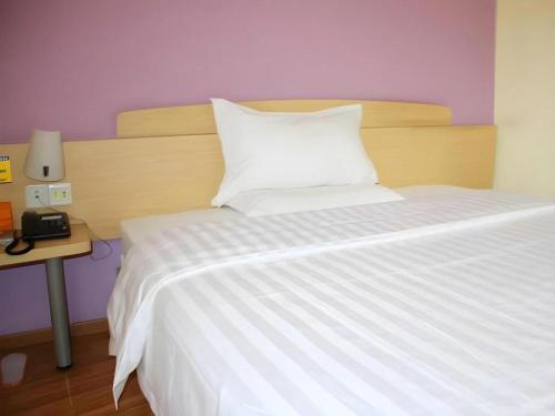 a bedroom with a white bed with a night stand and a table at 7 Days Premium Chongqing Longtou Temple North Railway Station Center in Chongqing