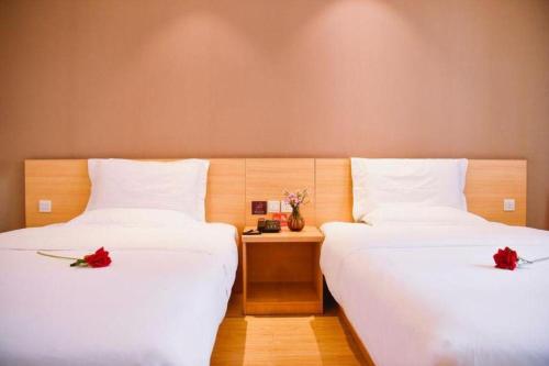 two beds in a room with red roses on them at 7 Days Premium Chongqing Longtou Temple North Railway Station Center in Chongqing