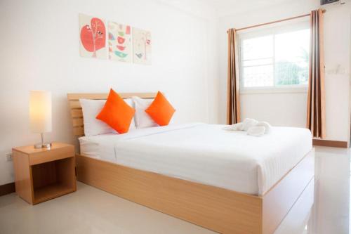 a bedroom with a bed with orange pillows and a window at Meesuk ChiangRai Hotel in Chiang Rai