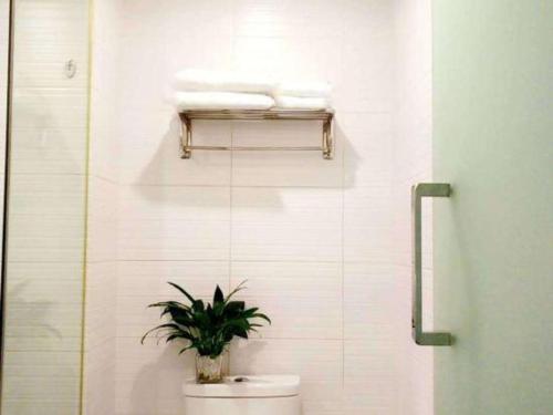 a bathroom with a toilet and a plant on a shelf at 7 Days Premium Chongqing Longtou Temple North Railway Station Center in Chongqing