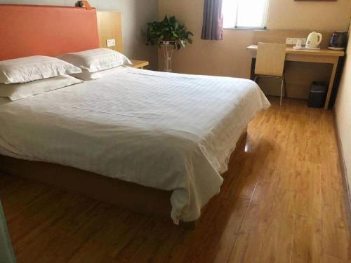 a bedroom with a large white bed and a desk at 7Days Inn Xuzhou Normal University Yunlong Mountain in Xuzhou