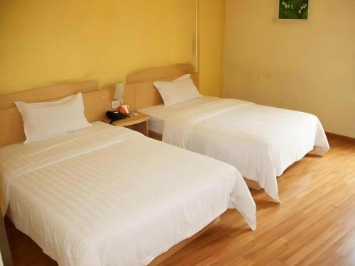 two beds in a hotel room with white sheets at 7 Days Premium Chongqing Longtou Temple North Railway Station Center in Chongqing