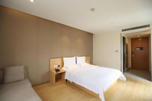 a bedroom with a large white bed and a couch at 7 Days Premium Chongqing Longtou Temple North Railway Station Center in Chongqing