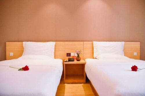 two beds in a hotel room with red roses on them at 7 Days Premium Chongqing Longtou Temple North Railway Station Center in Chongqing