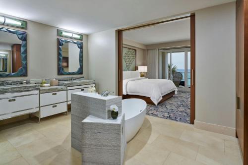 a bathroom with a tub and a bedroom with a bed at The St. Regis Bermuda Resort in Saint George