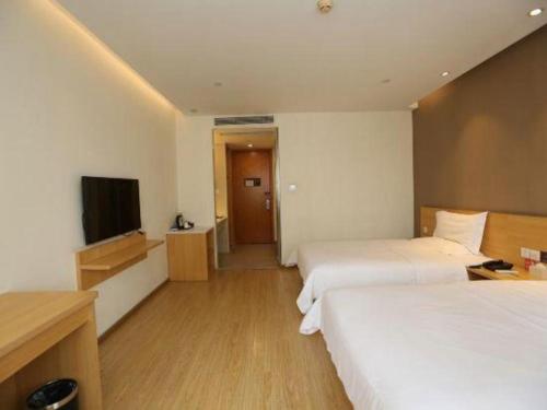 a hotel room with two beds and a flat screen tv at 7 Days Premium Chongqing Longtou Temple North Railway Station Center in Chongqing