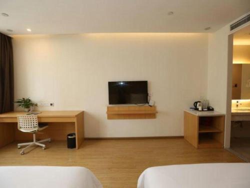 a bedroom with a desk and a tv on the wall at 7 Days Premium Chongqing Longtou Temple North Railway Station Center in Chongqing