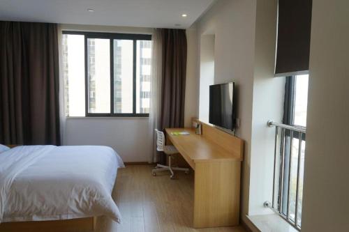 a hotel room with a bed and a desk and a television at 7 Days Premium Chongqing Longtou Temple North Railway Station Center in Chongqing