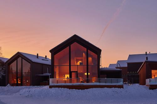 a glass house in the snow at sunset at Stay North - The House of Northern Lights in Äkäslompolo