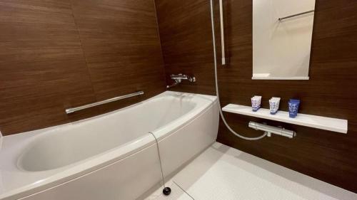 a white bath tub in a bathroom with wooden walls at KEIKYU EX Hotel Takanawa (Shinagawa Station) in Tokyo