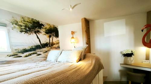 une chambre avec un lit avec un tableau sur le mur dans l'établissement Le Flamant Rose de Lilo'Salins, à Hyères