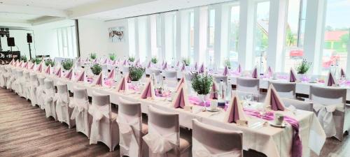 a row of tables with white chairs and pink napkins at Hotel Krone in Königsbrunn