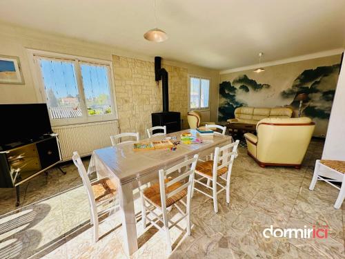 ein Wohnzimmer mit Tisch und Stühlen in der Unterkunft SOLEIL LEVANT - Terrasse, clim, jardin & BBQ in Arvert