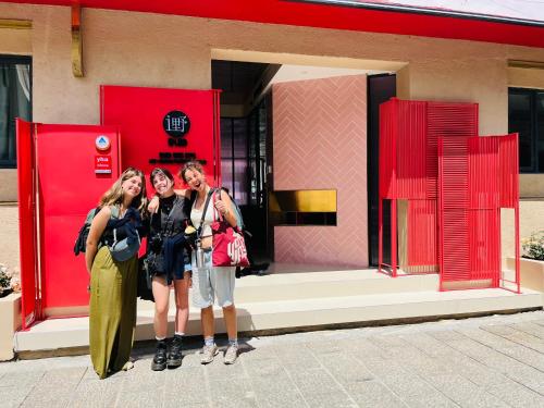 three women standing in front of a red store at Dali Upland International Youth Hostel, near the south gate of the ancient city ,5 mins walk to the old town, Close to Er Hai Lake, convenient payment and visa cards are accepted in Dali
