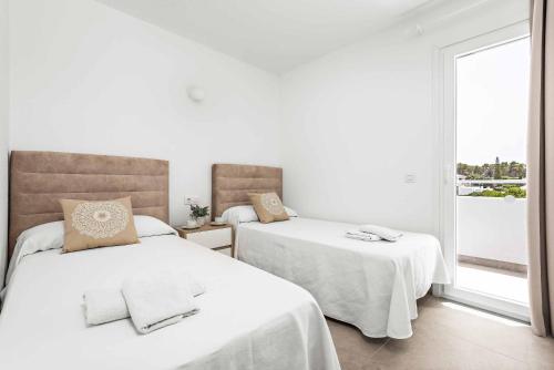 two beds in a white room with a window at Casa Maria in Cala Galdana
