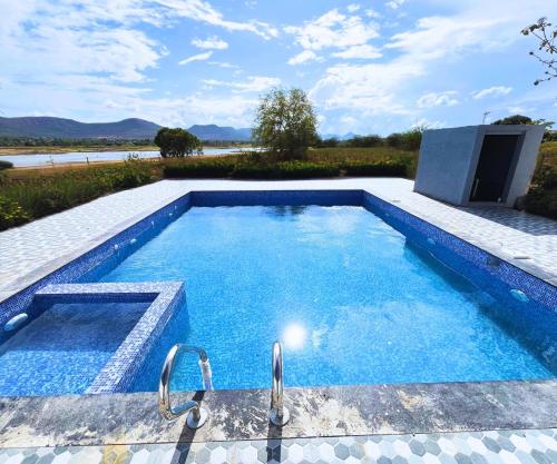 a large swimming pool with blue water in a backyard at Sizzle Bay Resort in Pune