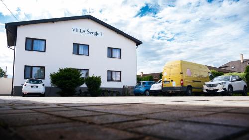 a white building with cars parked in a parking lot at SergJuli Villa in Plavecký Štvrtok