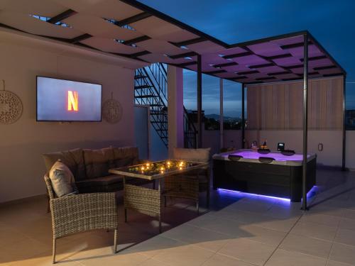 a living room with a tv and a couch and a table at JACUZZI penthouse - King's view in Artemida