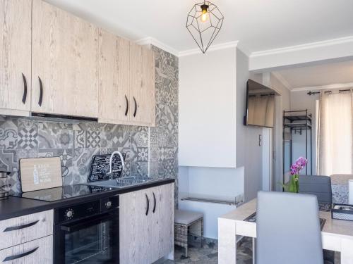 a kitchen with white cabinets and a table and chairs at JACUZZI penthouse - King's view in Artemida