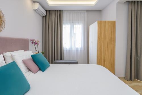 a bedroom with a white bed with blue and pink pillows at KORINA APART HOTEL KAVOS in Kavos